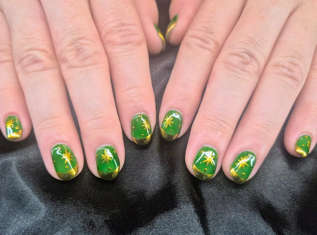 Short green nails with gold starbursts and glitter tips