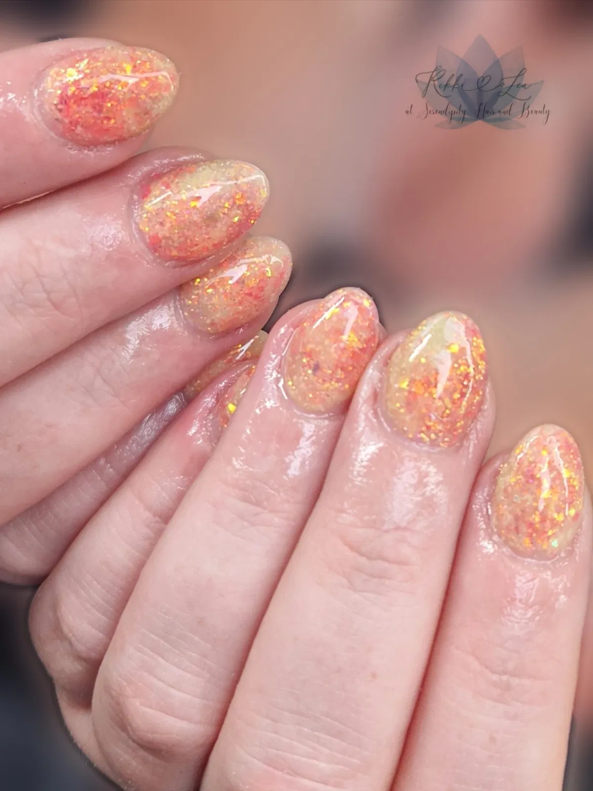 Glittery orange-gold wash on short oval nails