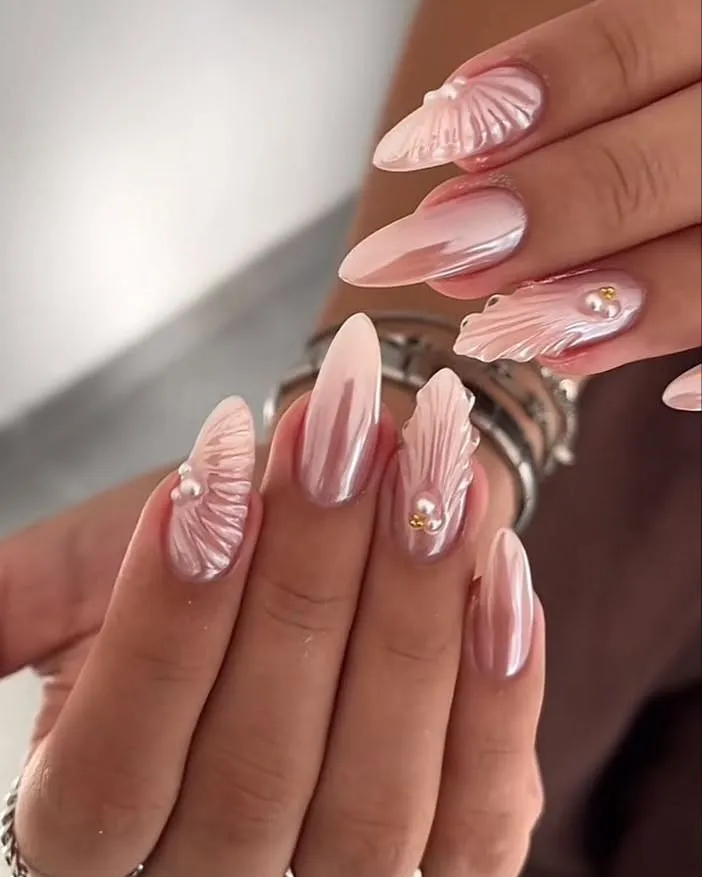 Pearly pink almond nails with raised feather-like textures and pearls