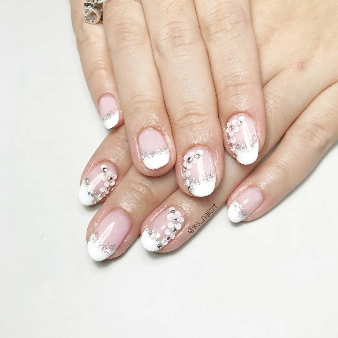 Pink French tips with silver glitter and floral embellishments