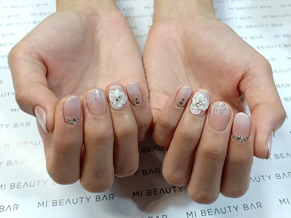 Muted pink nails with a raised white flower accent