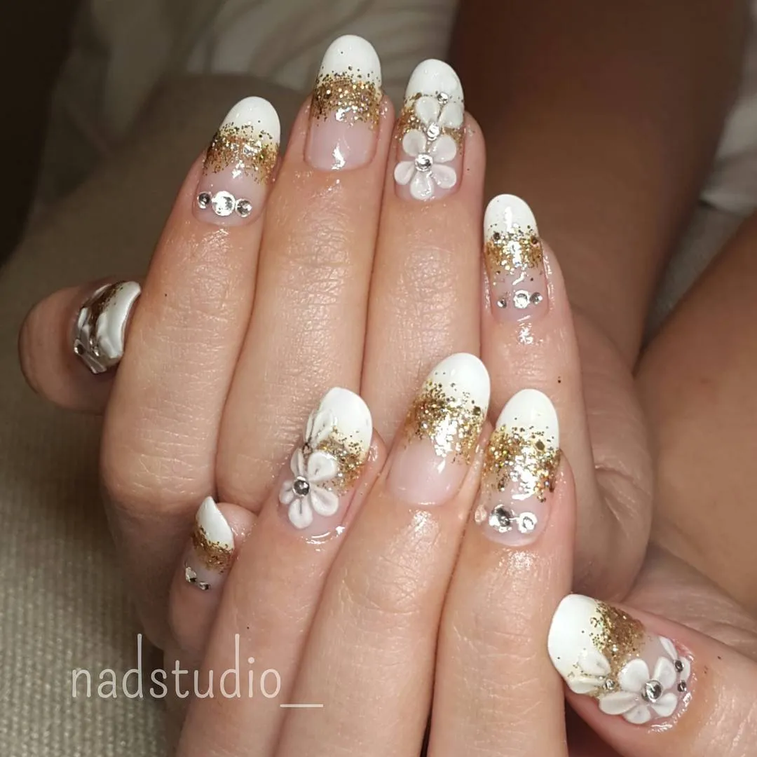 White French tips with gold glitter and raised floral accents