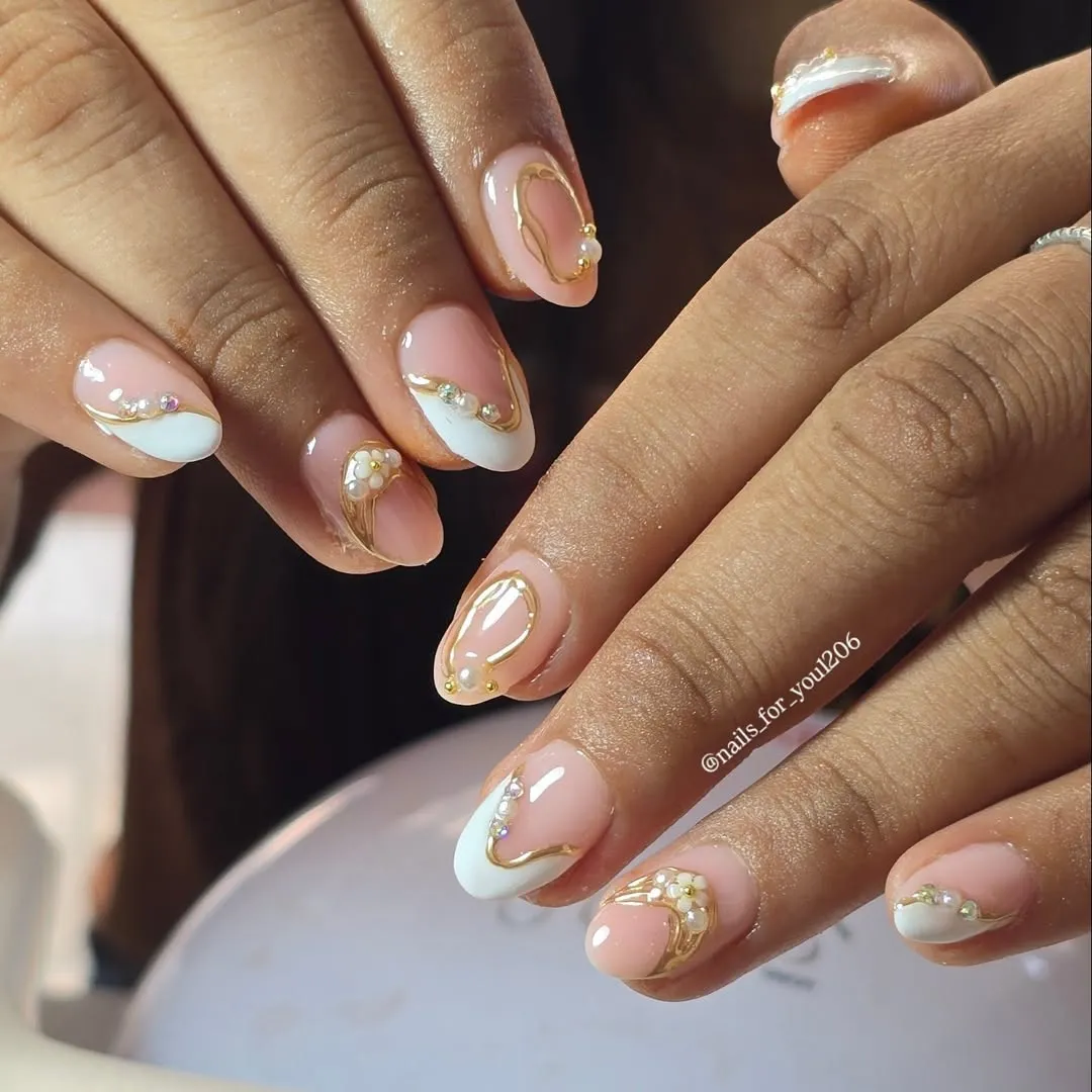 Short nude French tips with gold curves and pearl-like accents