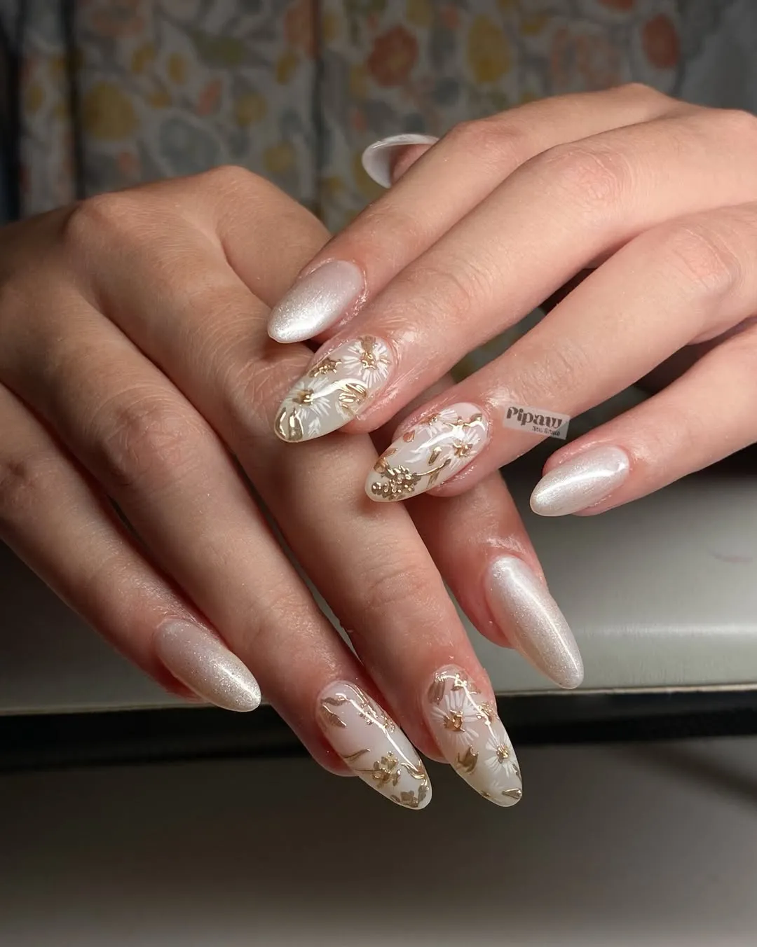 Pearly white shimmer with gold-accented floral nail art