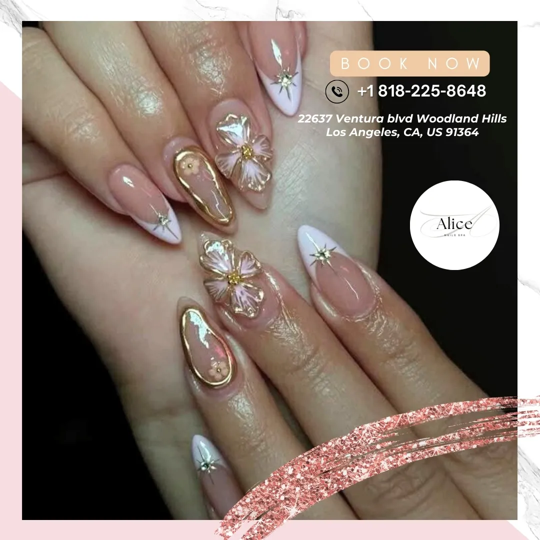 Long nude almond nails with V-French tips, gold outlines, and translucent flowers
