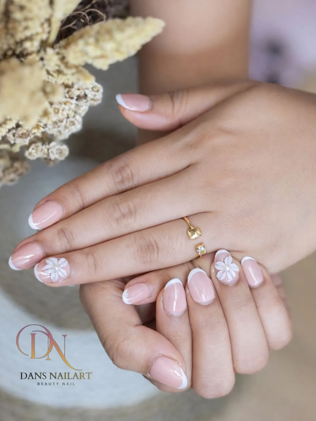 Pale pink French tips with raised white floral accents