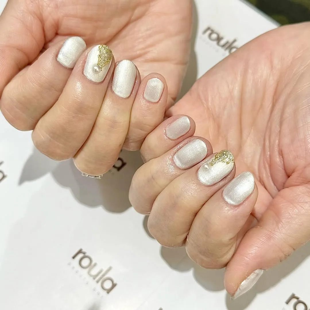 Pearly white nails with gold foil and pearl-like accents
