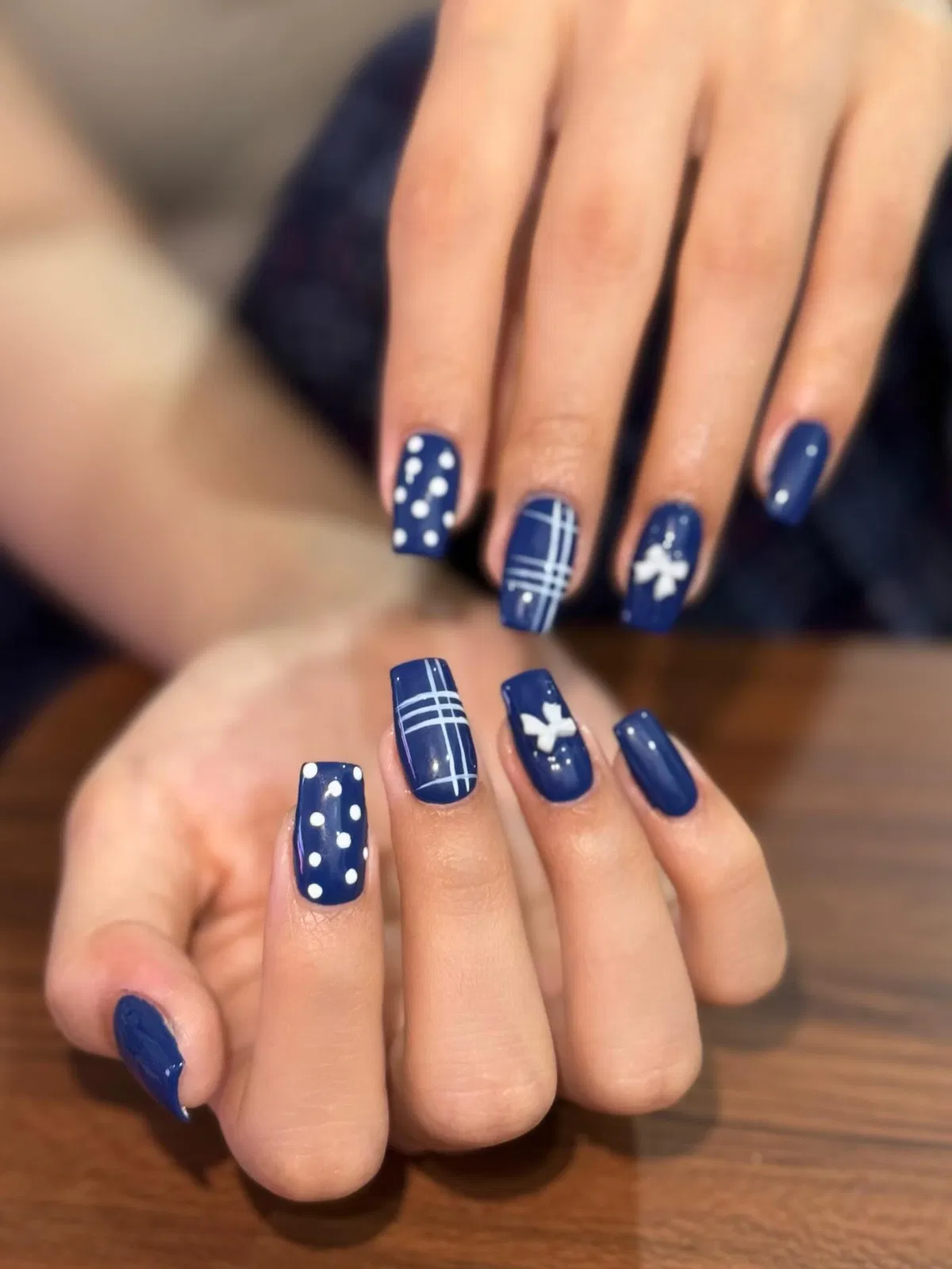 Navy square nails with polka dots, plaid lines, and bow graphic