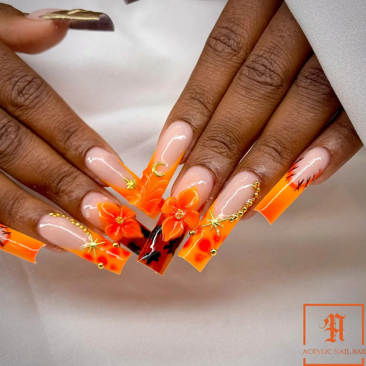 Orange French tips with 3D flowers and gold charm details