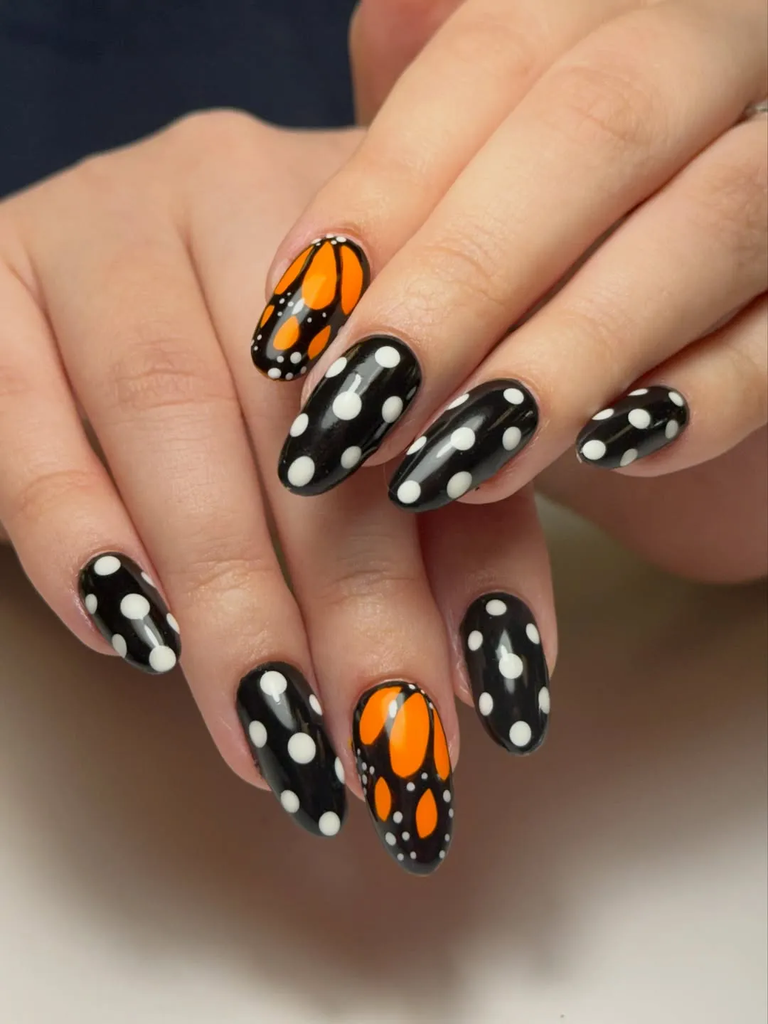 Black-and-white polka dots with orange accent nails
