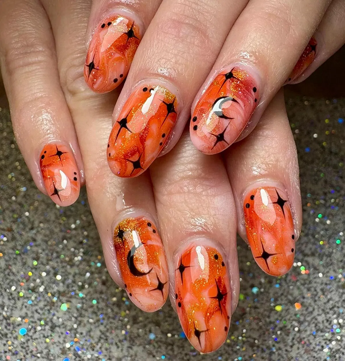 Orange marbled nails with black starbursts