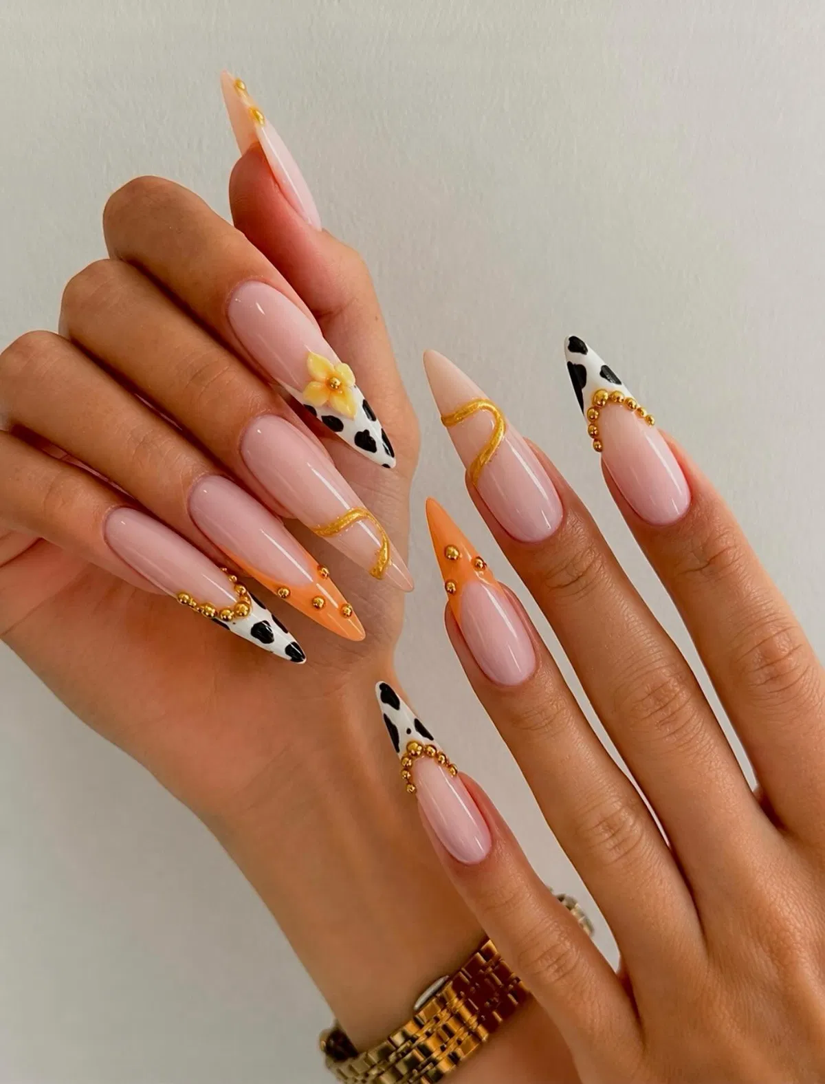 Nude base with orange tips, black spots, and gold accents