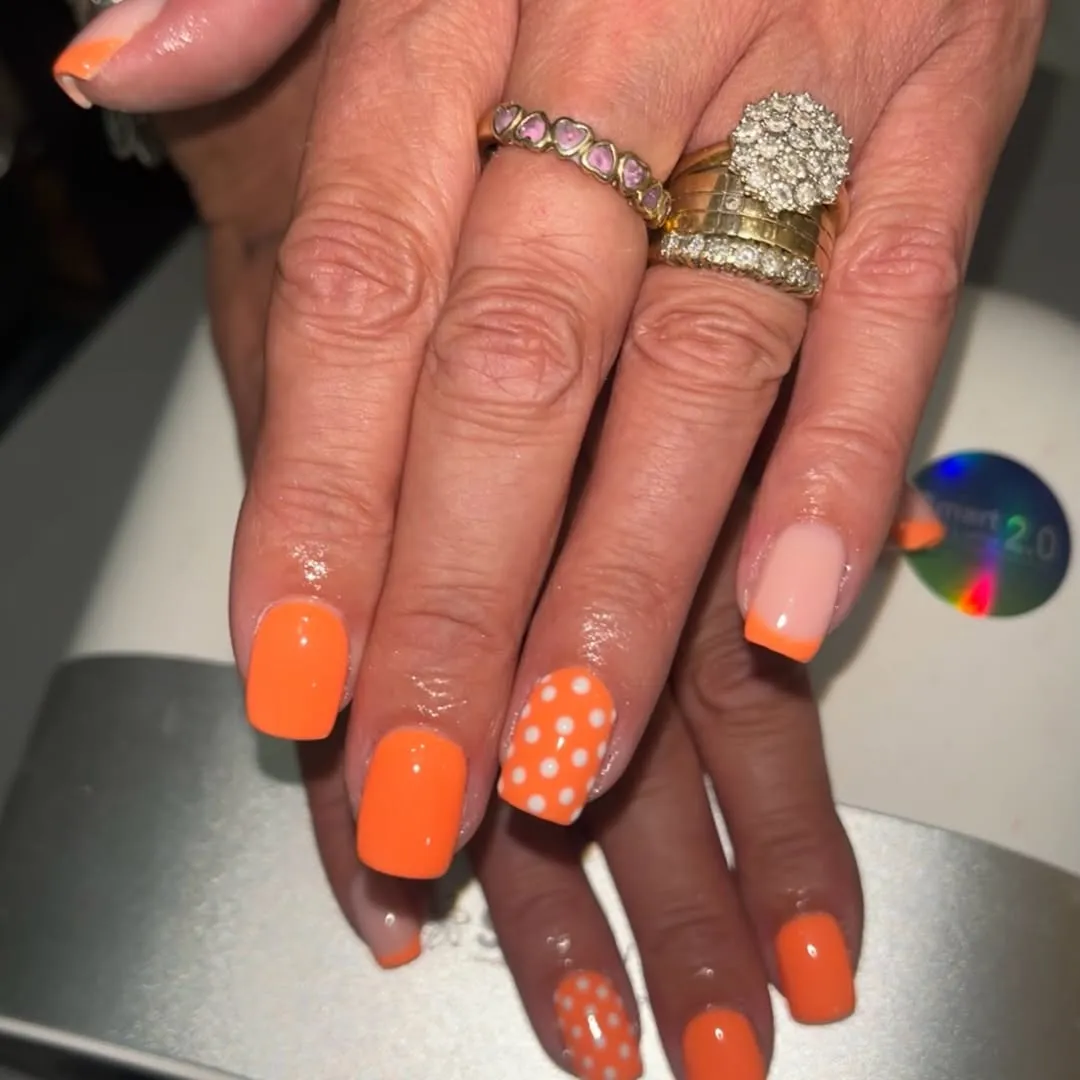 Bright orange square nails with polka-dot accent