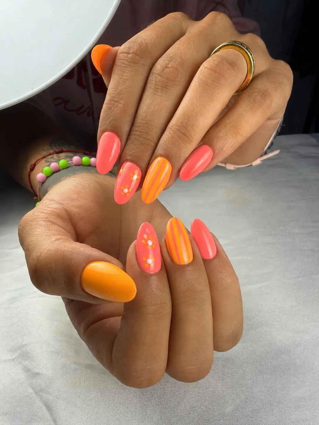 Coral and orange almond nails with stripes and dot accents