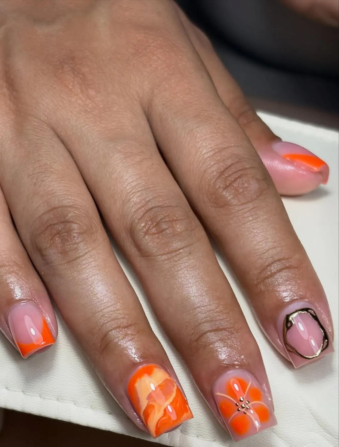 Nude-and-orange French tips with floral accent and metallic outline