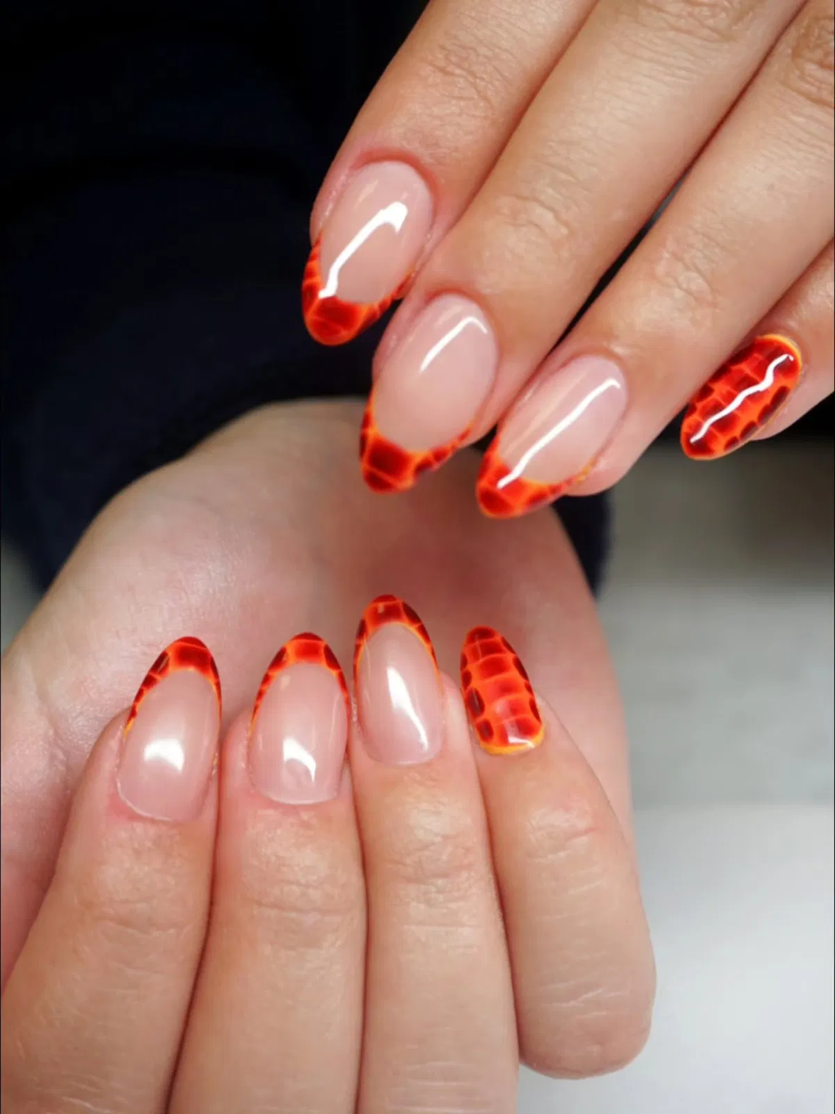 Orange-red patterned French tips on a nude base