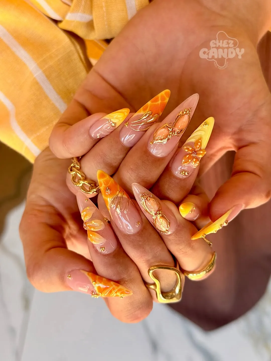 Ornate orange-yellow stilettos with 3D sculpting and gold embellishments