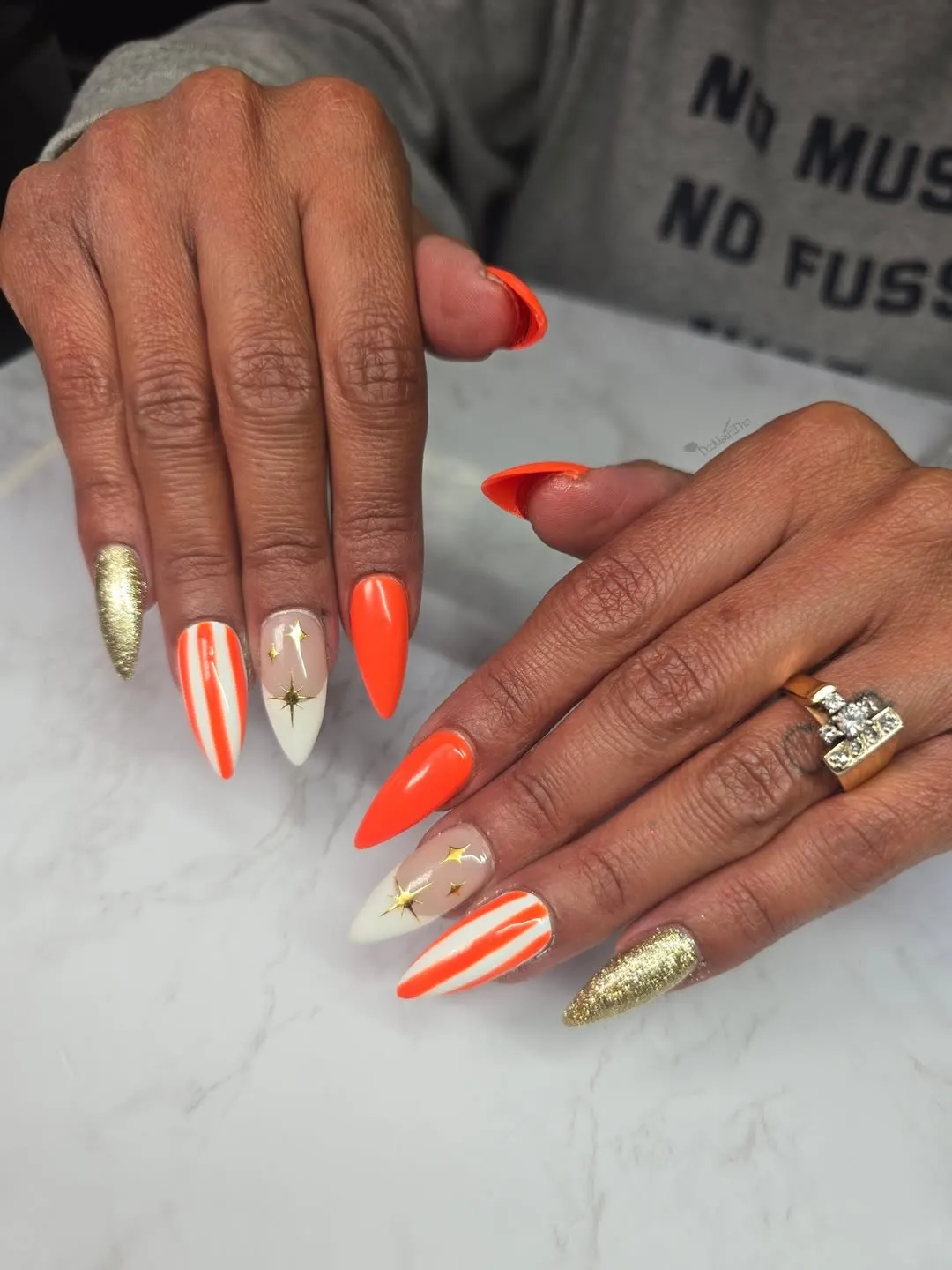 Neon orange stilettos with gold stars, stripes, and shimmer