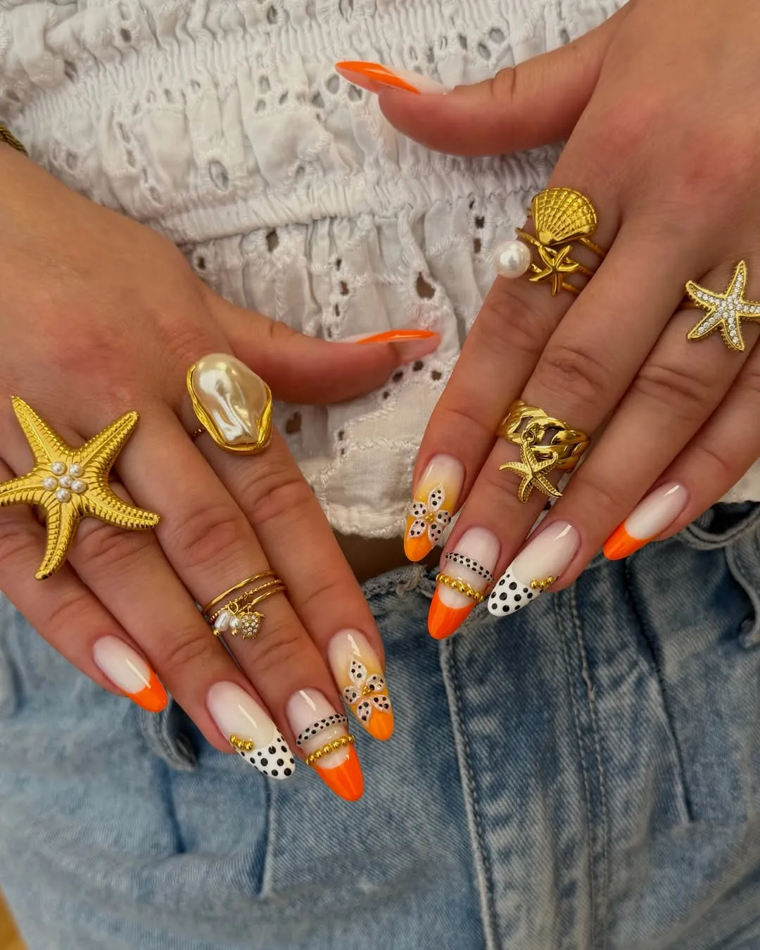 Orange French tips with black dots and gold bead accents
