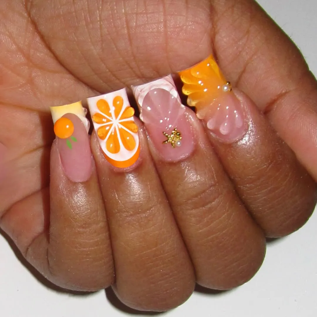 Citrus-style nail art with gold star charm and 3D orange accent
