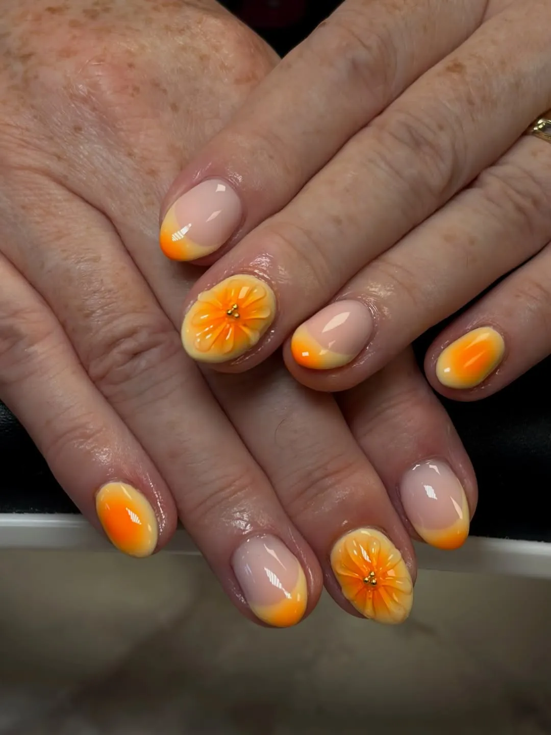 Soft nude base with orange ombrΓ© tips and raised flowers