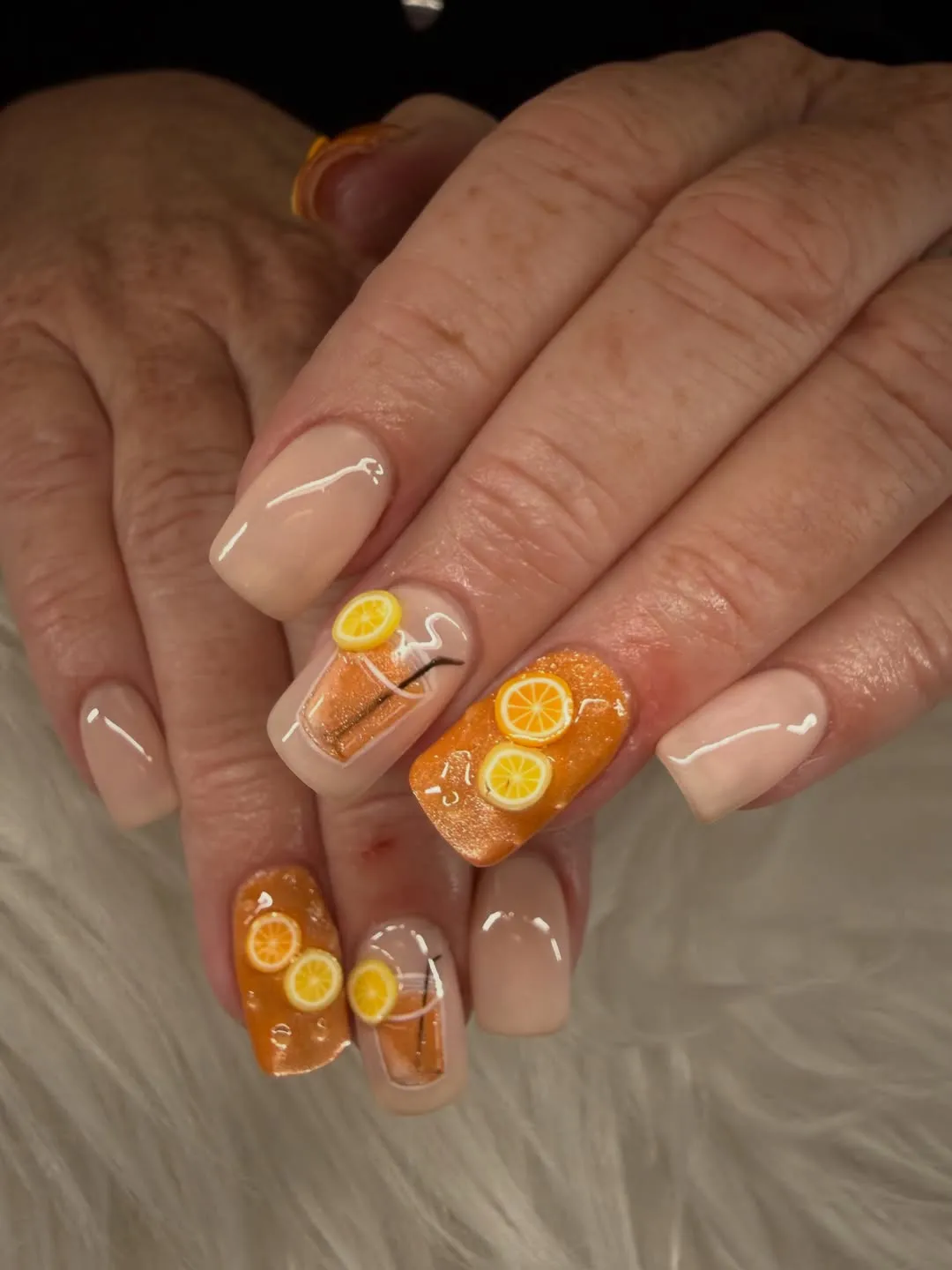 Nude nails with orange glitter and lemon drink art
