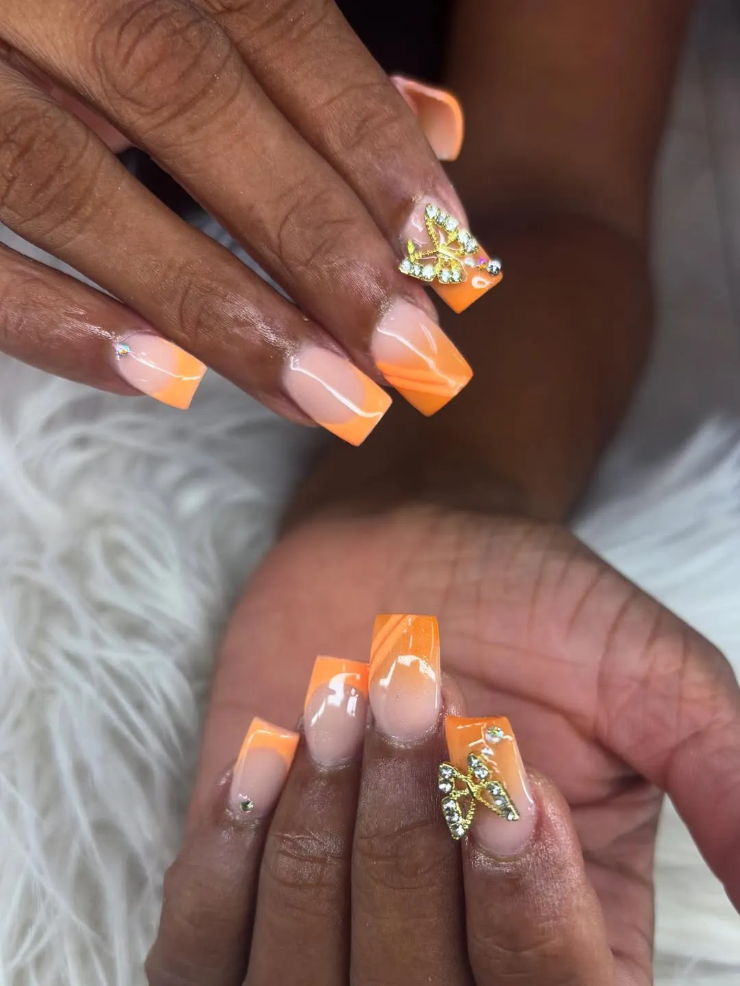 Square orange ombre tips with butterfly charm and swirl accents