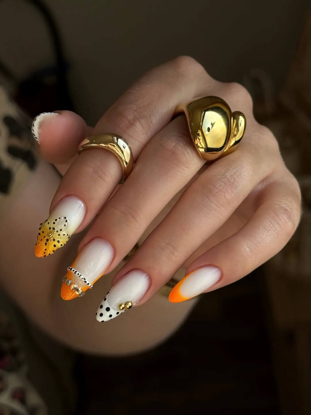 Long orange tips with polka dots and gem accents