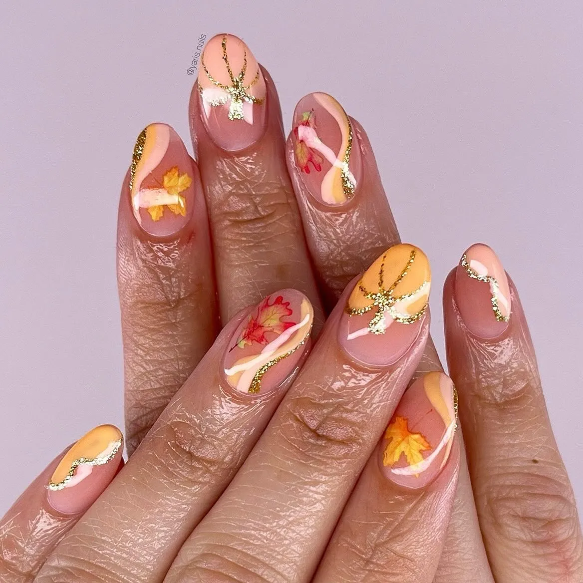 Nude base with pastel orange curves, gold glitter lines, and leaf art