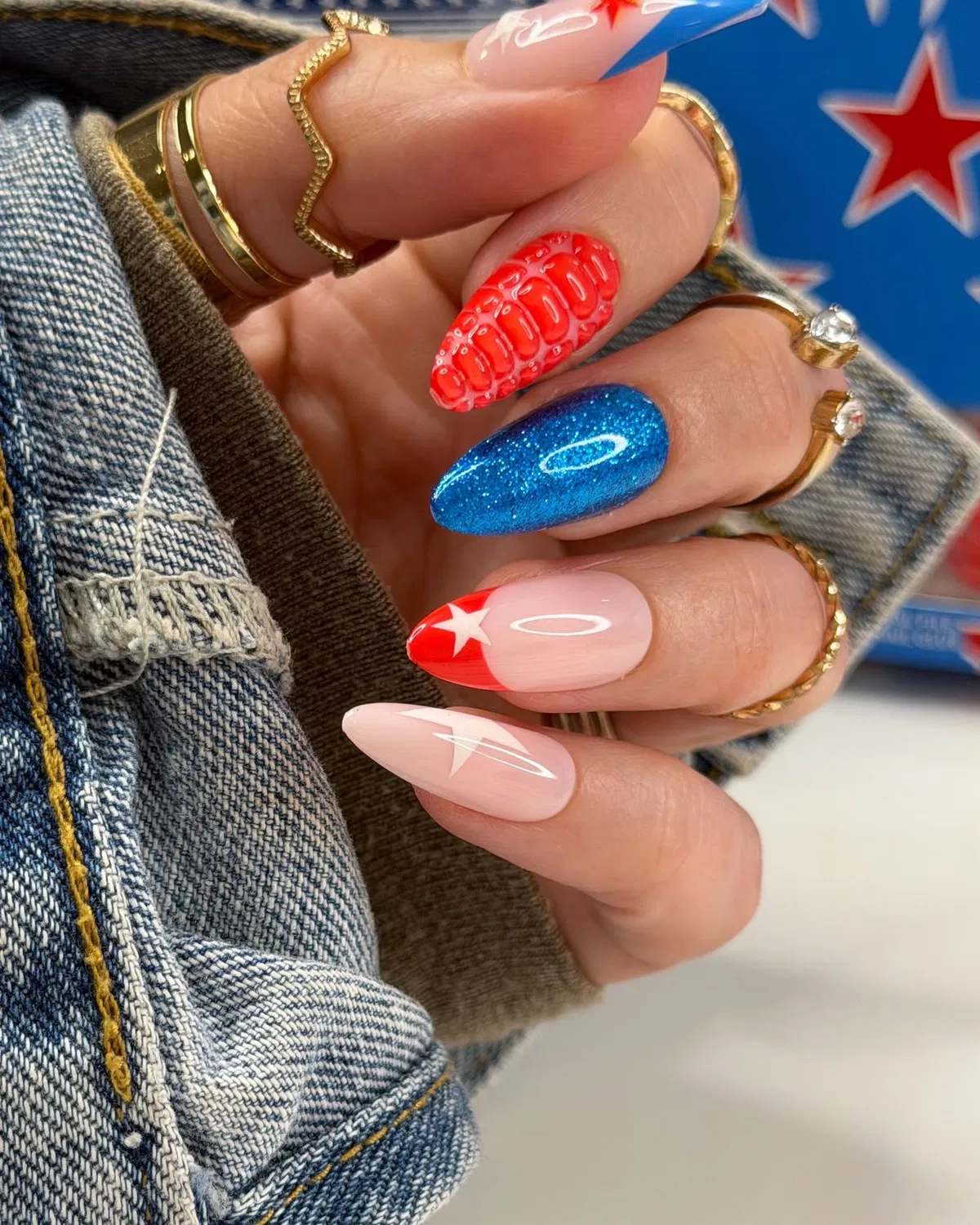 Textured red accent with glittery blue and star-tipped nude nails