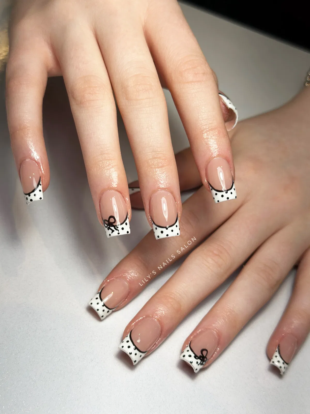 Square polka-dot French tips with black outline and bow detail