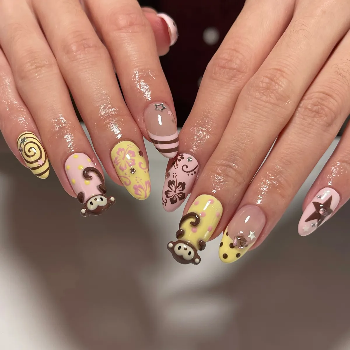 Playful mixed nail art with polka dots, swirls, stars, and raised character accents