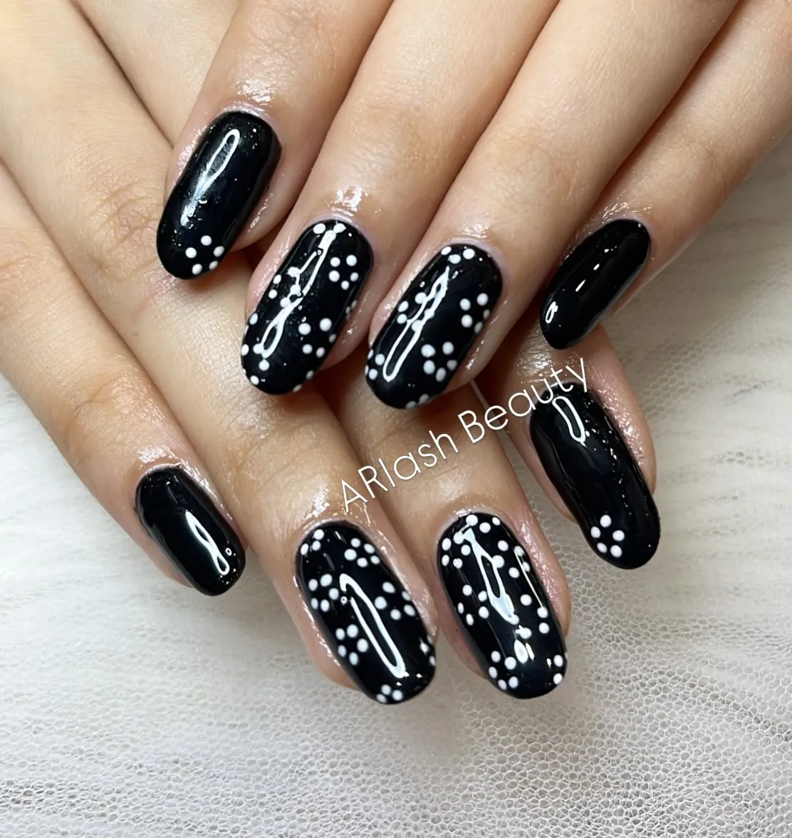 Glossy black nails with scattered white dot clusters
