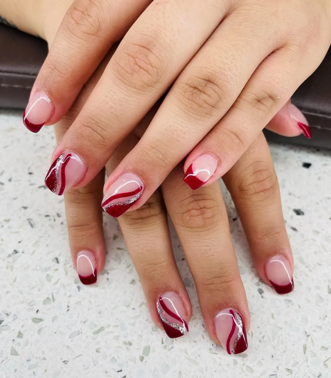 Curved red French tips with silver glitter swooshes