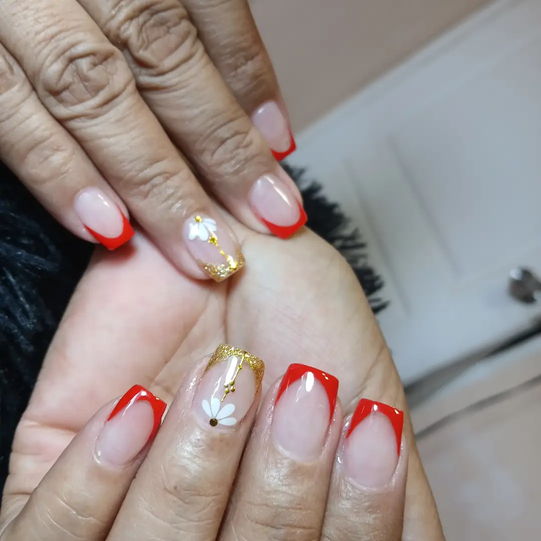 Red V-French tips with gold glitter and white floral details