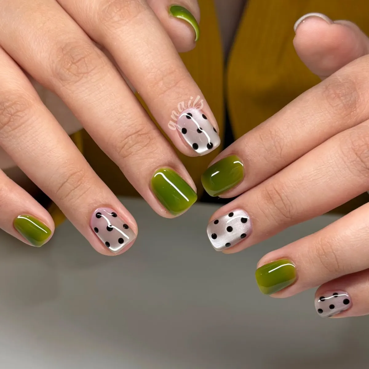 Olive green with black polka dot accents and a silver dotted nail