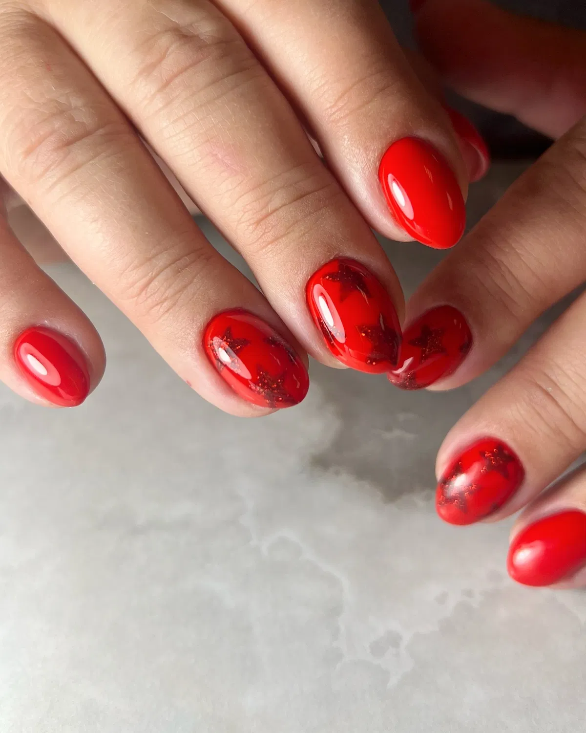 All-red glossy nails with darker star overlays