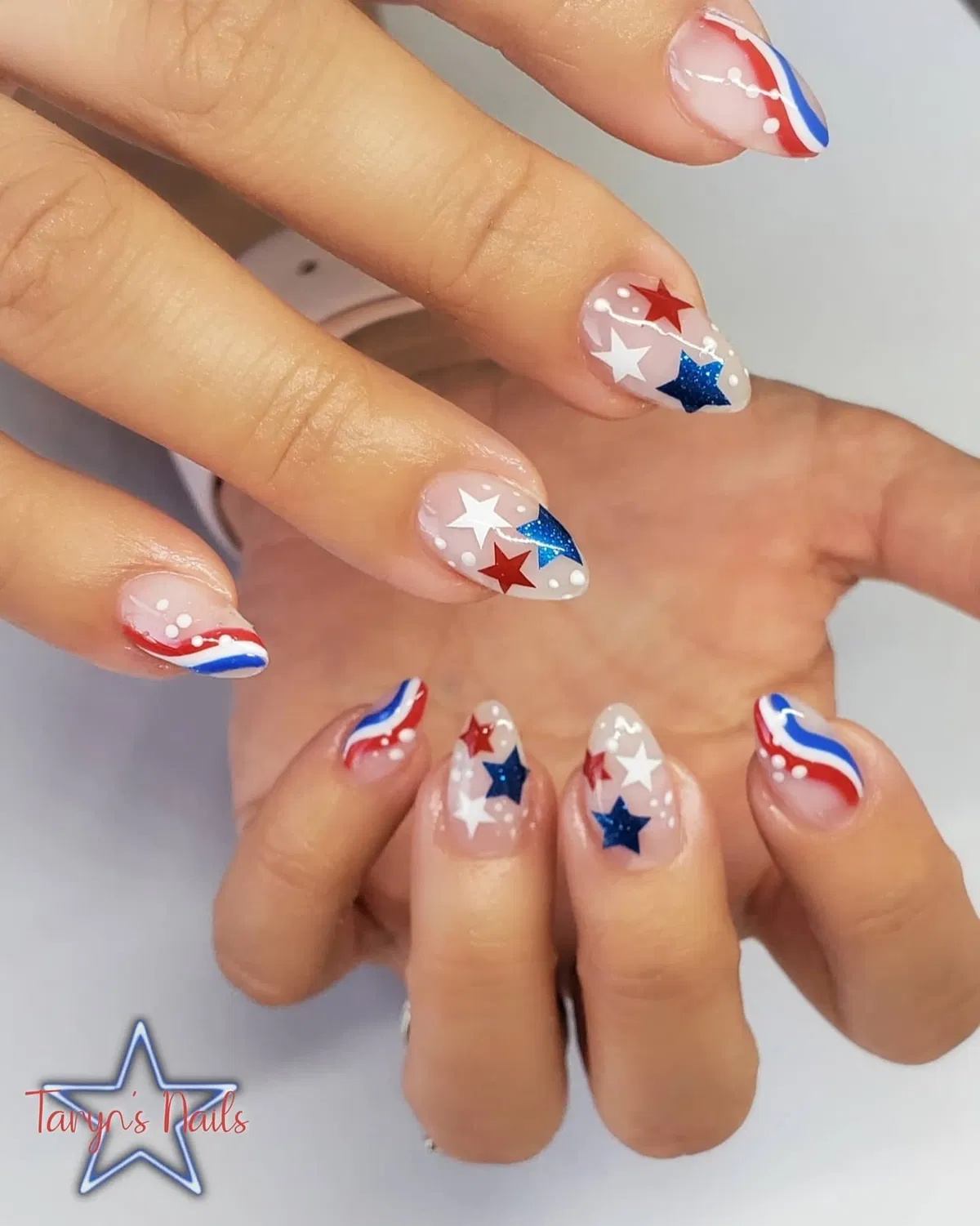 Nude almond nails with bold stars and wavy stripes
