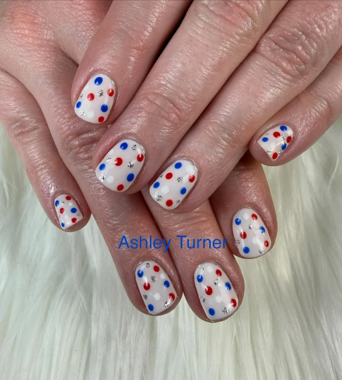 White nails with red/blue polka dots and silver specks
