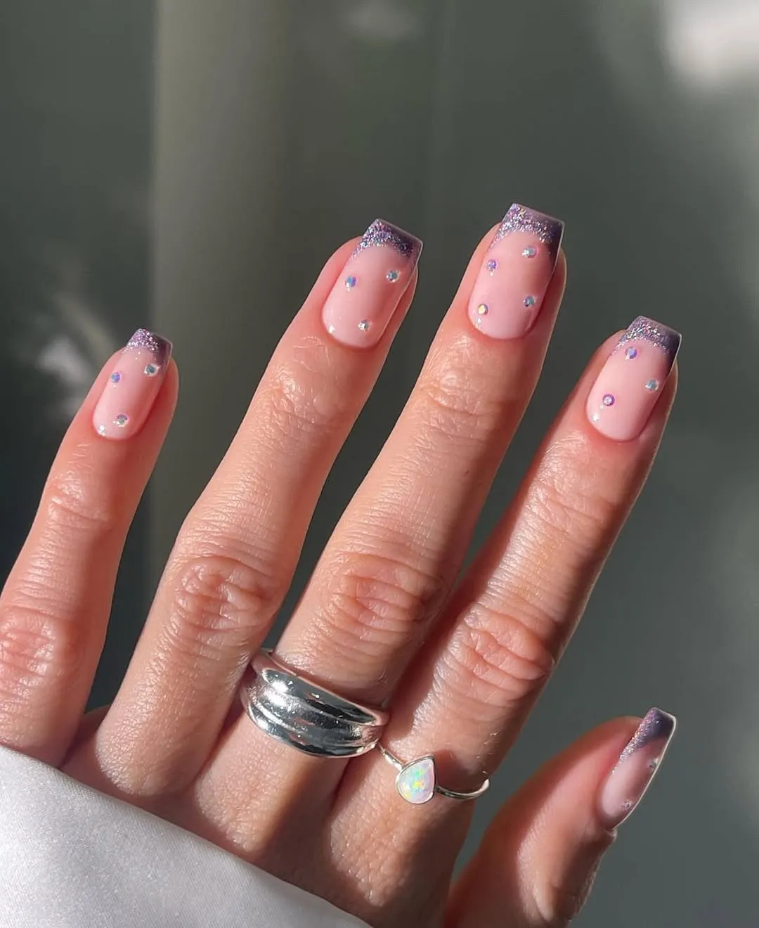 Pale pink square nails with purple glitter tips and iridescent studs