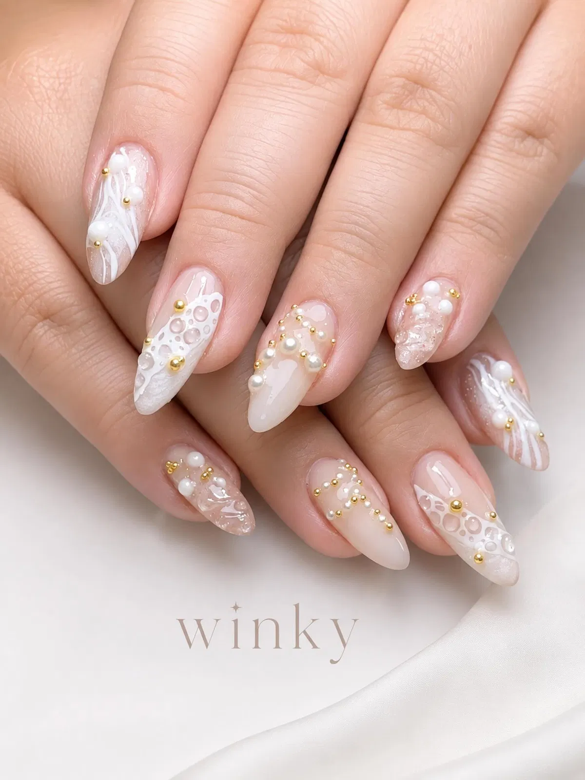 Sheer nude nails with white lace-like art and pearl accents