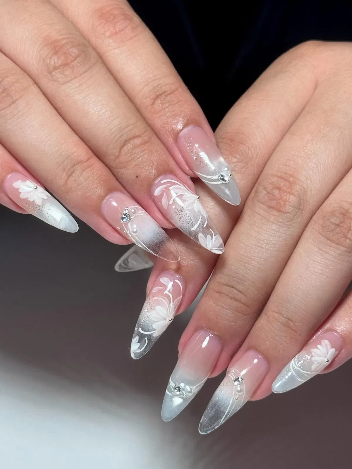 Sheer pink stilettos with translucent glitter tips and white florals