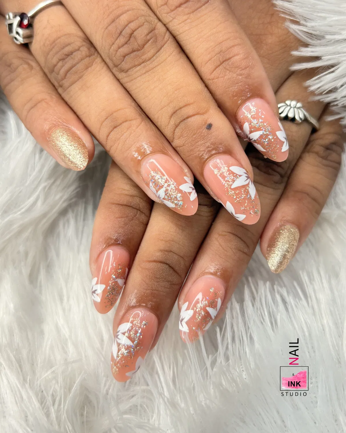 Peach nude nails with white leaf silhouettes and silver glitter