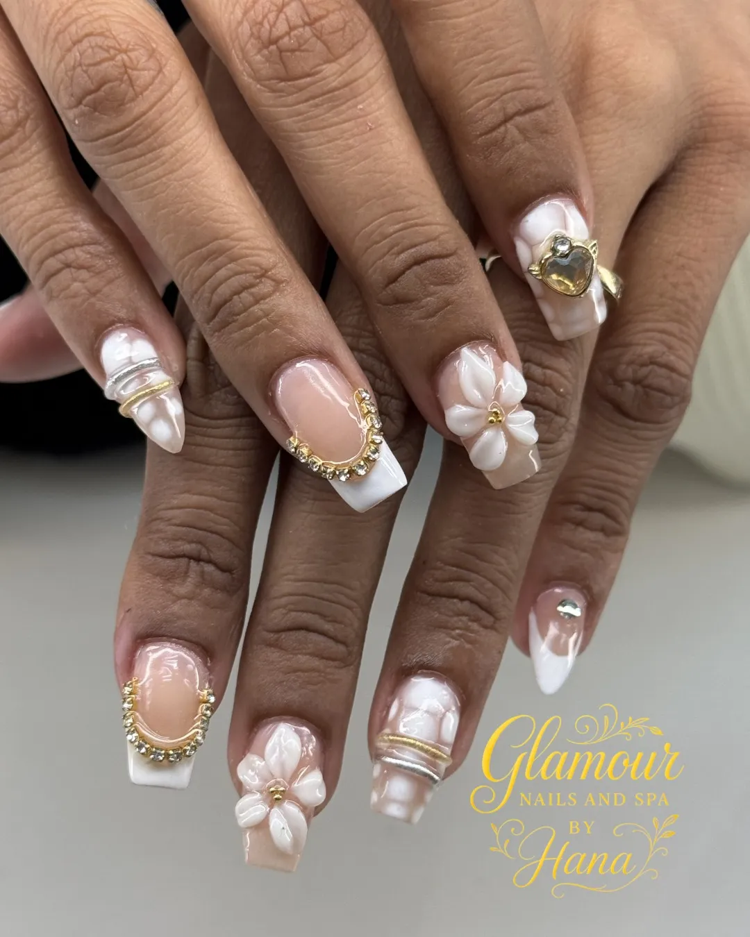 Nude-pink French tips with gold frames, rhinestones, and 3D flowers