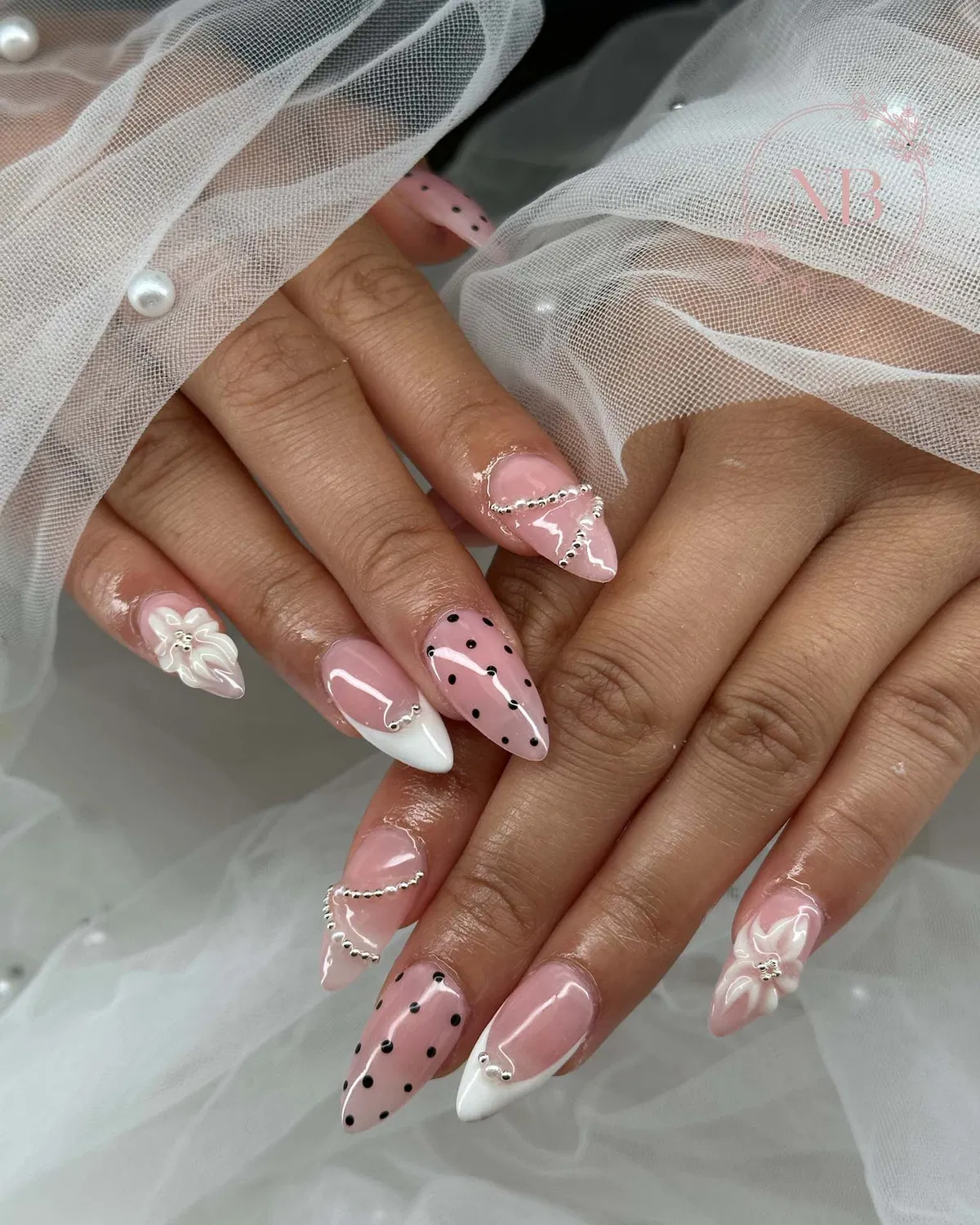 Pink stiletto nails with polka dots, French tips, and silver bead accents