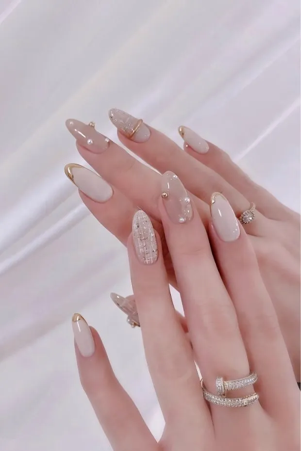 Milky nude with gold-outlined tips and bow accent