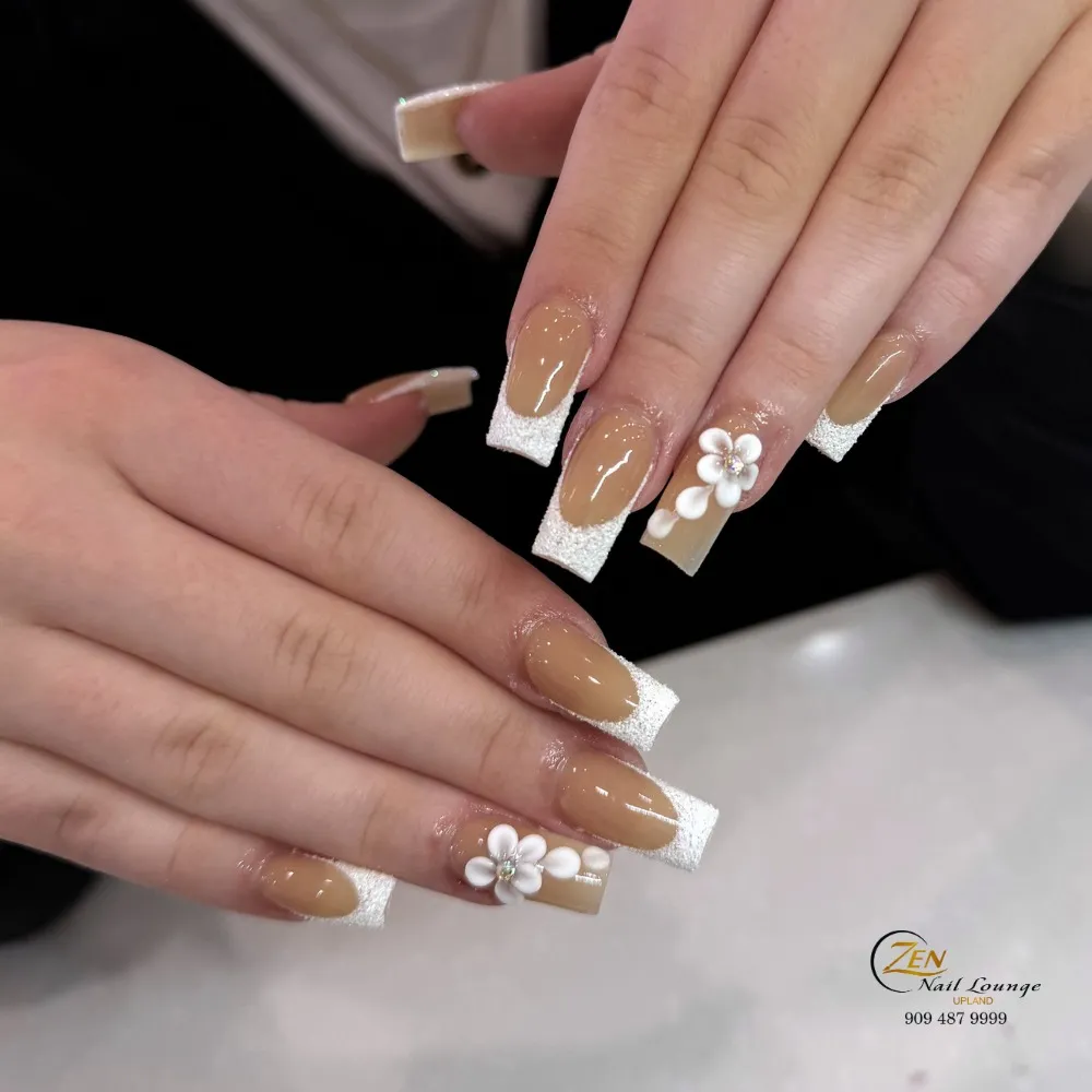 Warm nude square nails with textured white tips and 3D flower