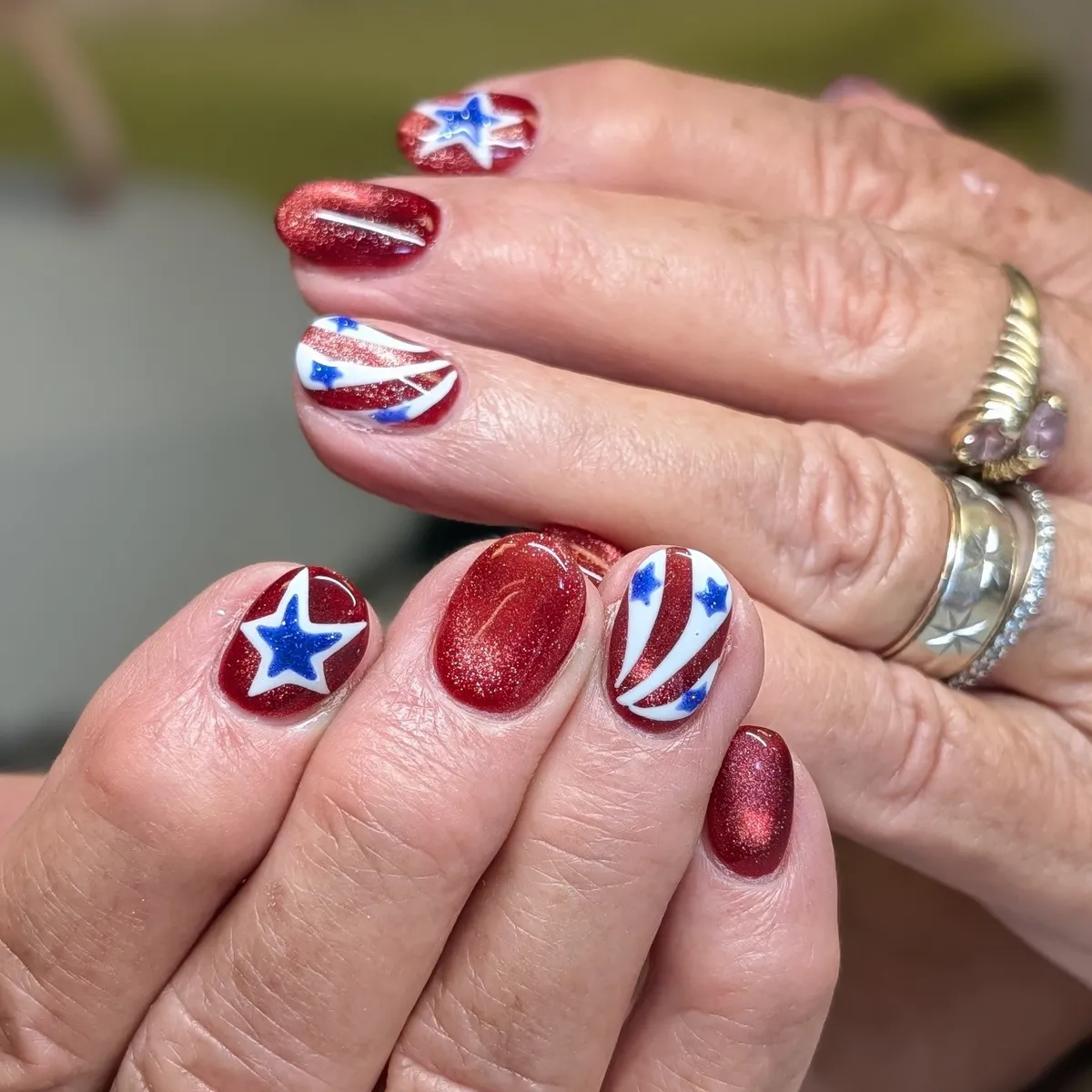 Shimmery red nails with blue star accents