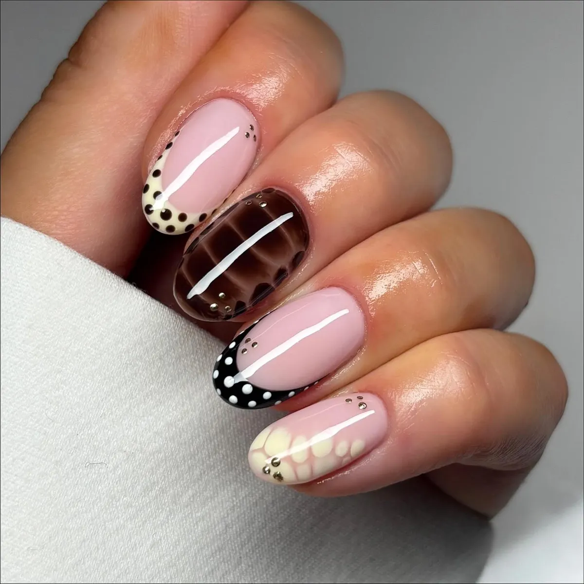 Pink nails with mixed polka dot tips and a brown grid accent nail