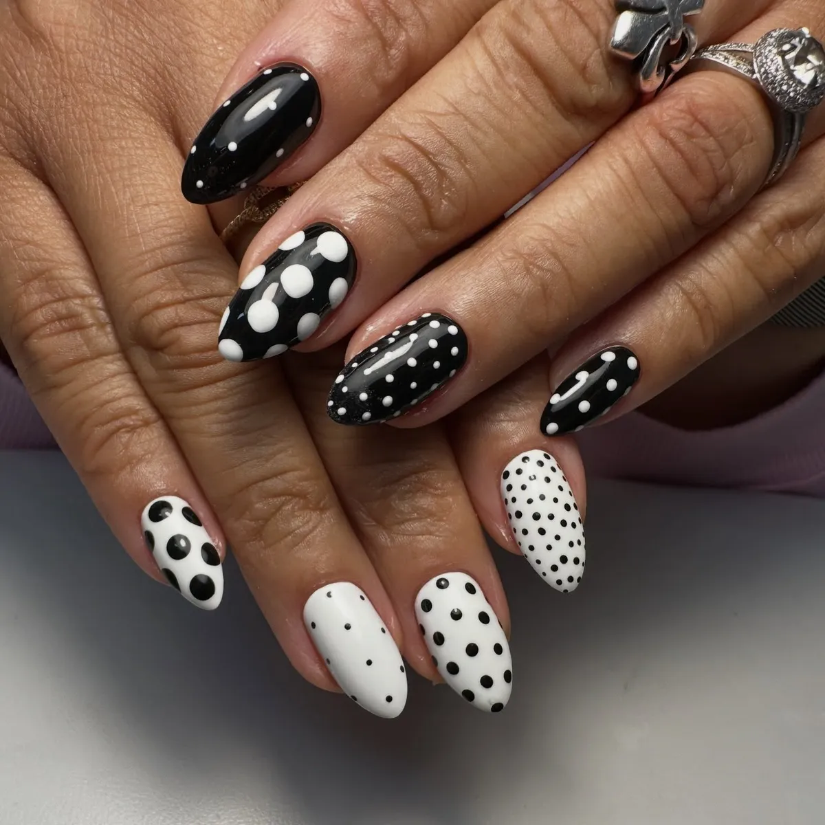 Alternating black and white polka dot nails in mixed dot sizes